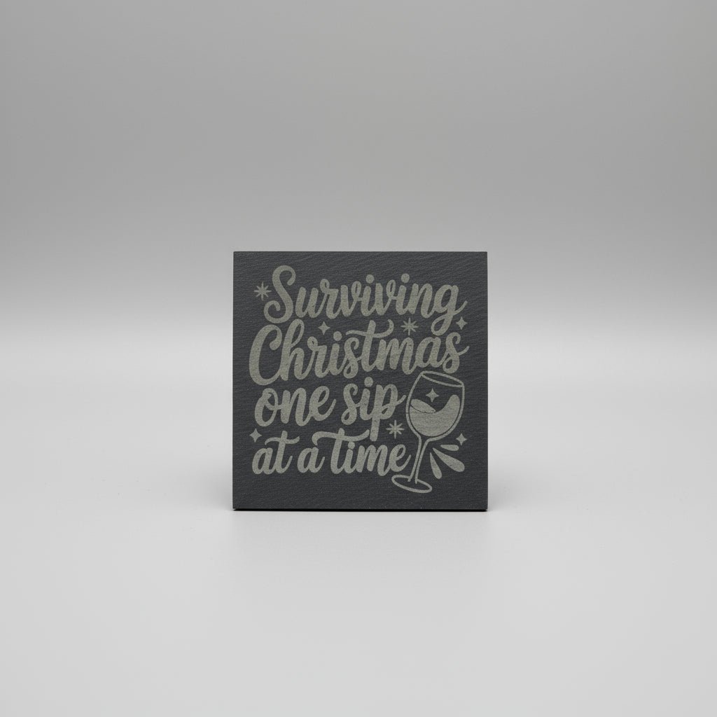 Decorative sign with text 'Surviving Christmas one sip at a time' on a gray background
