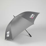 A dark gray open umbrella with white printed text reading 'C.RYAN' and a large white '33' near the lower edge, photographed indoors on a gray carpeted floor.