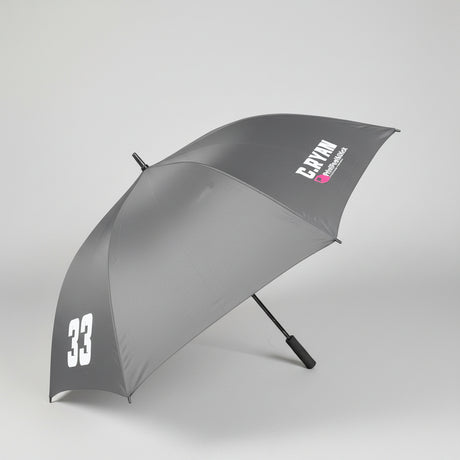 A dark gray open umbrella with white printed text reading 'C.RYAN' and a large white '33' near the lower edge, photographed indoors on a gray carpeted floor.