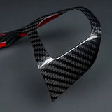 A glossy carbon fiber trim piece with a black and gray woven pattern and red inner lining, shown on a dark gray background.