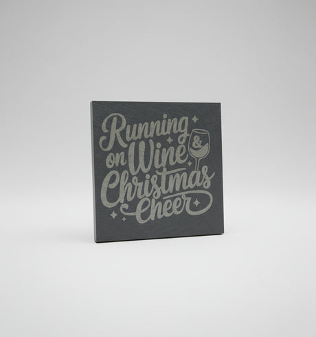 Slate coaster with 'Running on Wine Christmas Cheer' text and wine glass graphic on a gray surface.