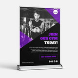A compact desktop roller banner featuring a male fitness model with text that encourages joining a gym today, along with contact information and social media links.