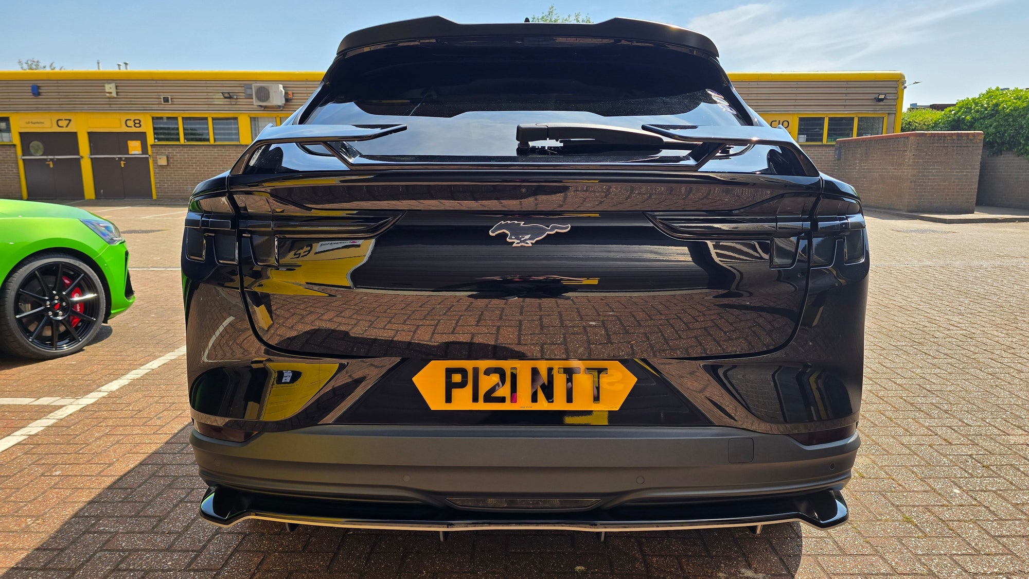 Black car with a yellow license plate in an outdoor setting