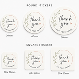 A set of round and square thank you order stickers shown in three sizes (30mm, 40mm, 50mm) on a light gray background. The stickers are cream-colored with a delicate green leaf wreath design and a small pink heart, with 'thank you' written in elegant black script.