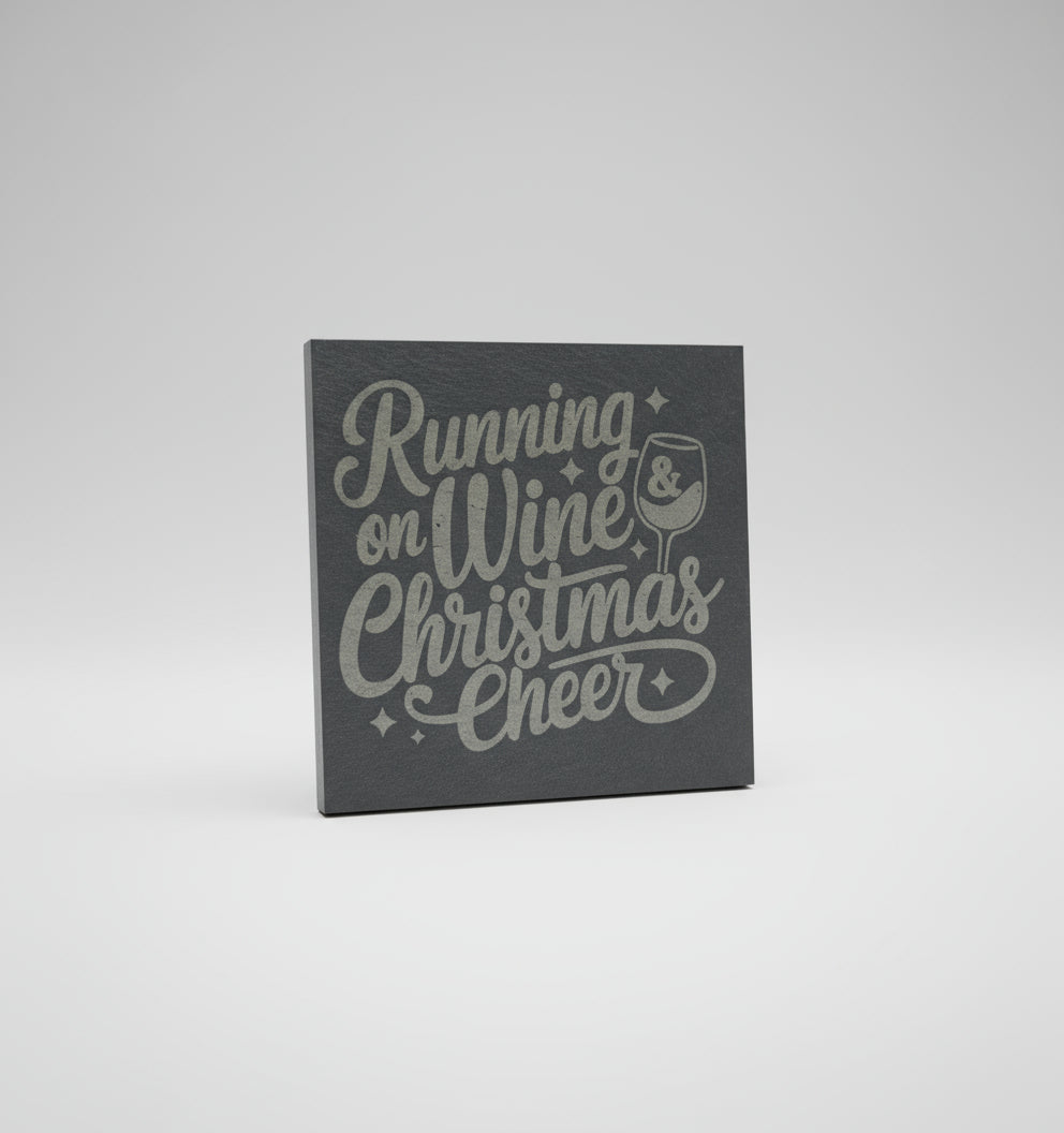 Slate coaster with 'Running on Wine Christmas Cheer' text and wine glass graphic on a gray surface.