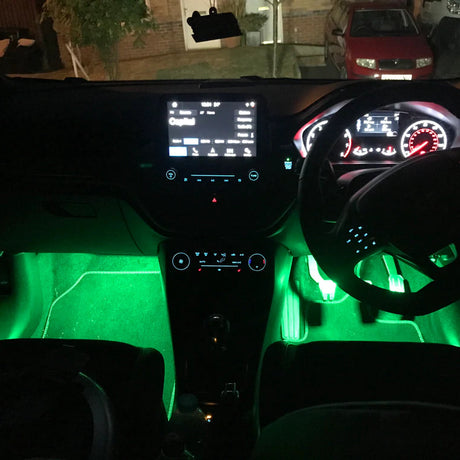 Car interior with green LED lighting, dashboard, steering wheel, and seats.
