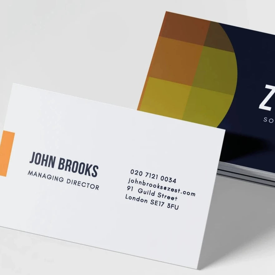 A stack of laminated business cards with velvet texture, featuring a color block design in orange, blue, and yellow at the top, and a white card with printed business information in the front.